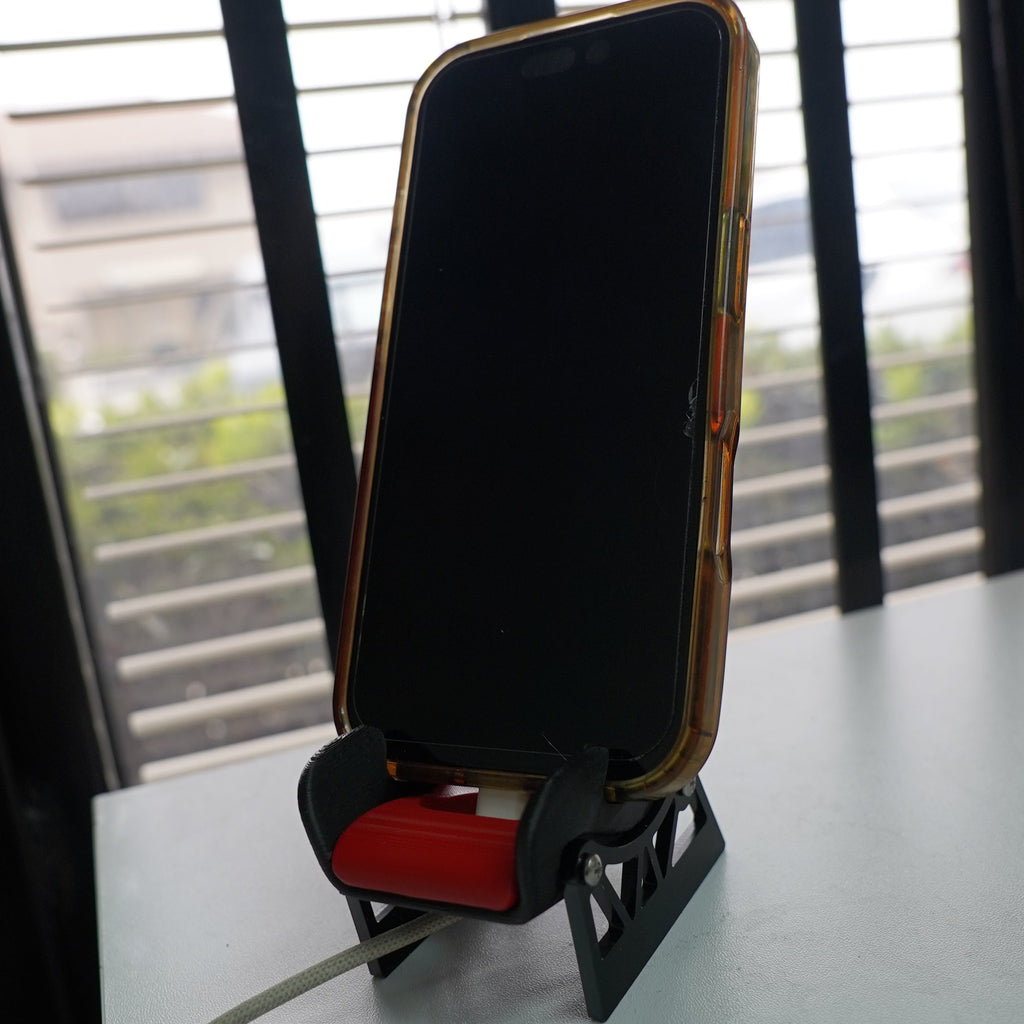 Phone case with a stand on a table in front of window blinds